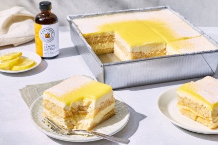 A pan of lemon tiramisu with a few slices removed and a bottle of King Arthur Pure Lemon Extract in the background